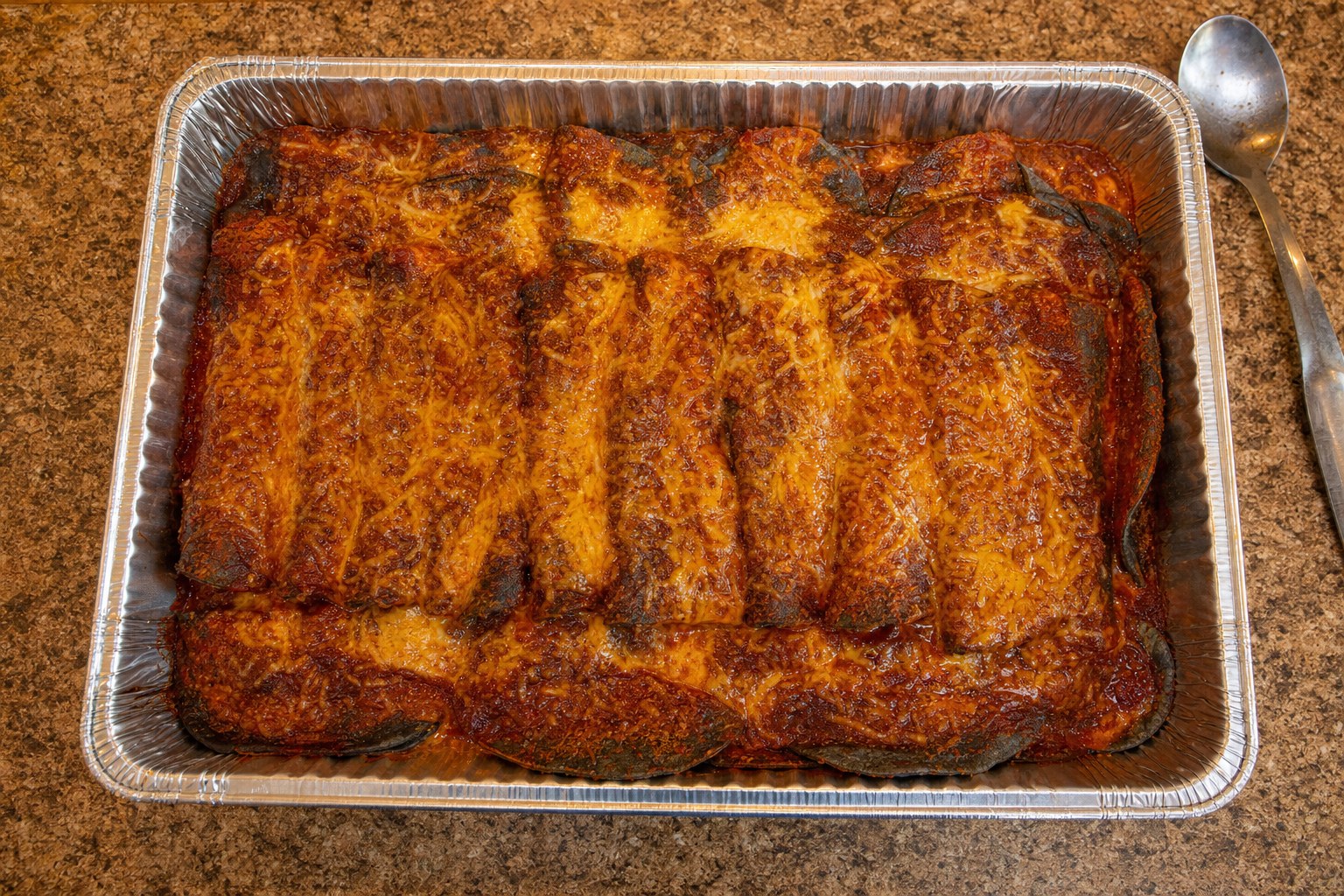 Large tray of stacked blue corn enchiladas ready for a group